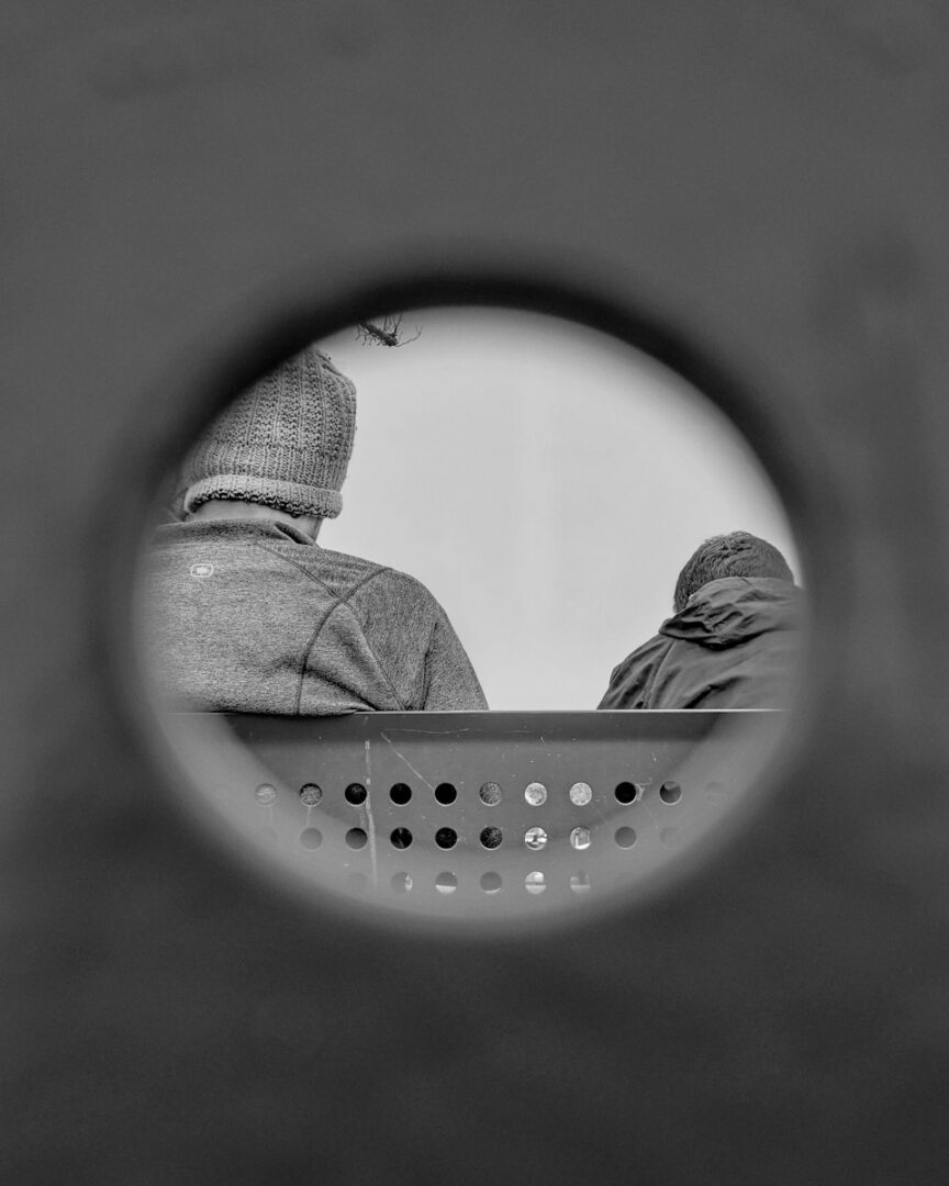 person in gray knit cap looking at round mirror